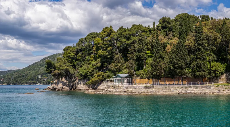 Il promontorio del Bagno Ducale visto dal mare, con la vegetazione fitta e la piccola costruzione sulla scogliera