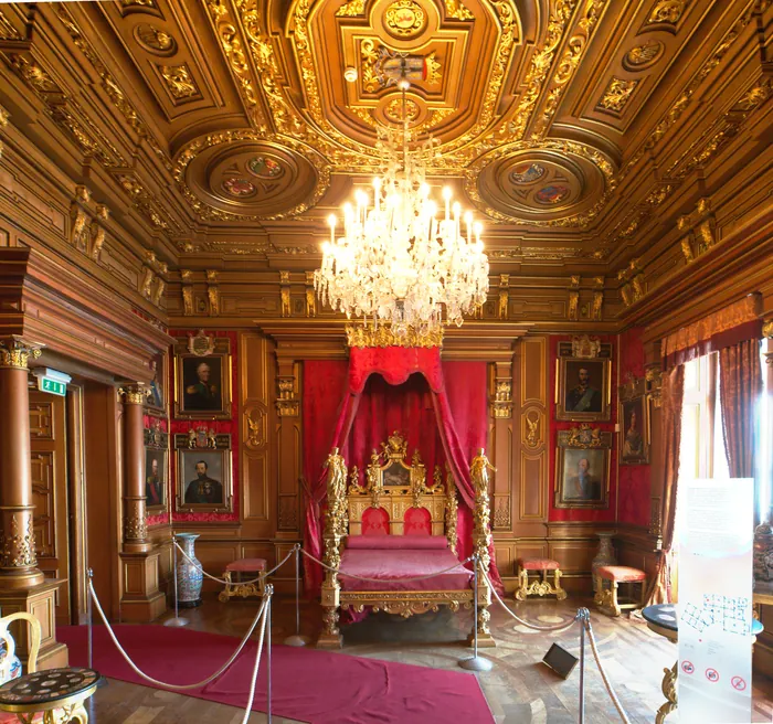 Una camera da letto del castello con il baldacchino rosso e il soffitto a cassettoni dorati