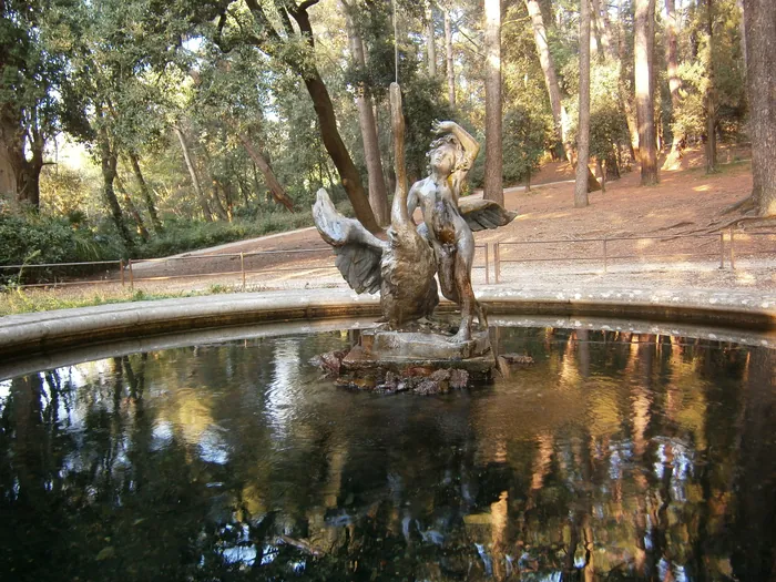 Una fontana nel bosco del parco con una scultura al centro e i riflessi degli alberi