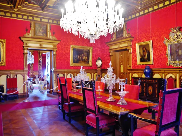 La sala da pranzo con la tavola apparecchiata, le pareti rosse e i lampadari
