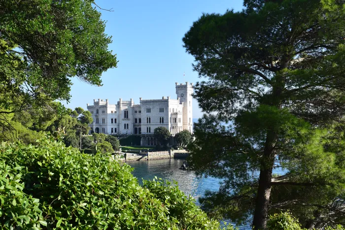 Il mare turchese dell'area marina protetta davanti al castello, visto tra i pini del parco