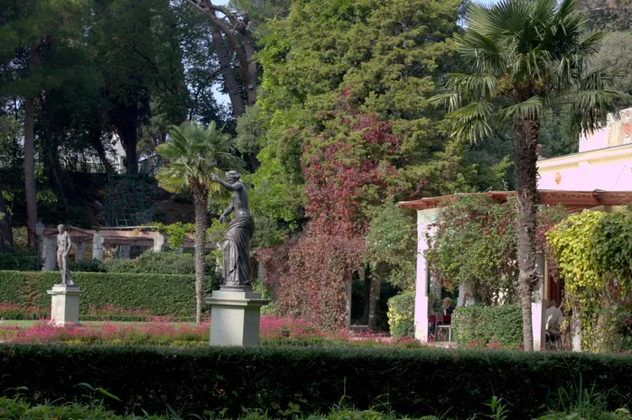 Il giardino con le statue su alti piedistalli tra le aiuole e le palme